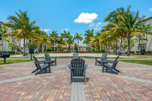 A set of four chairs and a table are arranged in a circle on a brick patio.