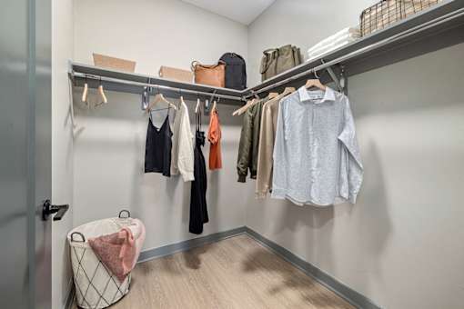 a walk in closet with a rack of clothes and a bag