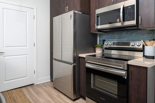 A modern kitchen with a stainless steel refrigerator, microwave, and oven.