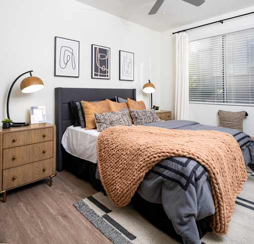 A bedroom with a bed covered in a large orange blanket.