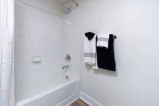 A white bathroom with a white tub and a white shower curtain.