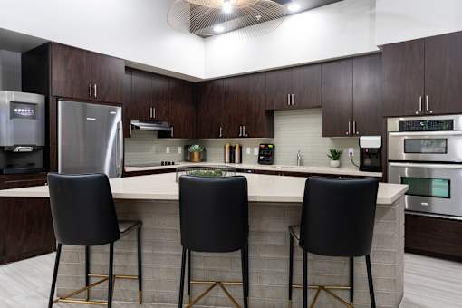 A kitchen with a bar area and three black chairs.