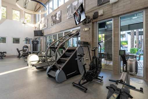 A gym with a variety of exercise equipment including treadmills, stationary bikes, and weight machines.