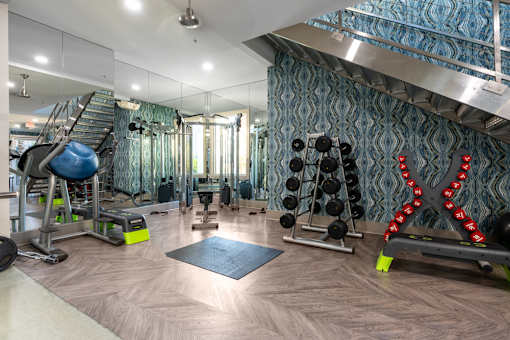 A gym with a variety of equipment including a bench, weights, and a mirror.