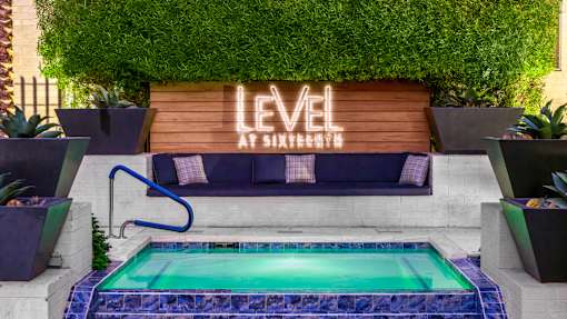 A pool with a blue tiled edge and a wooden sign that says "LEVEL" in front of a green wall.