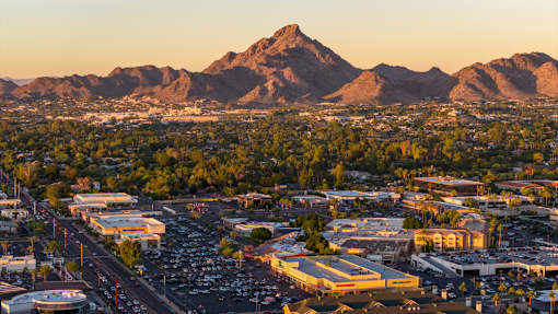 A cityscape with a mountain in the background during sunset.