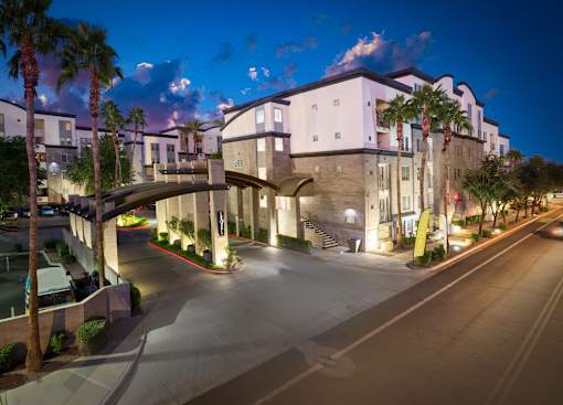A modern building with a curved entrance and palm trees in front.