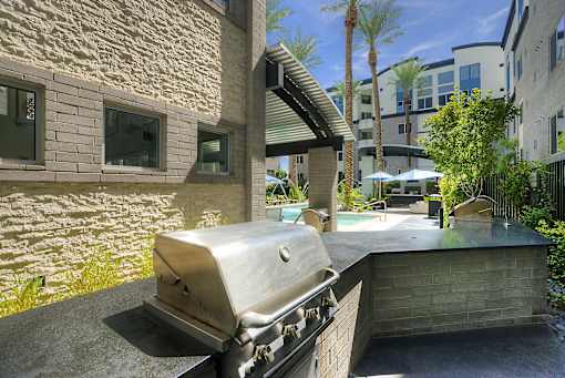 A BBQ grill is in the foreground of a patio area.