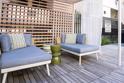 Two chairs with cushions and a table on a wooden deck.