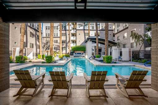 A pool with three chairs in front of a building.