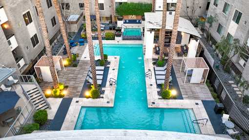 A swimming pool surrounded by palm trees and buildings.