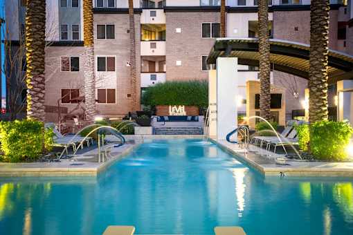 A swimming pool in front of a building with palm trees.