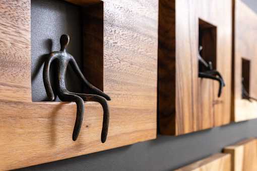 A black sculpture of a person is sitting in a wooden compartment.