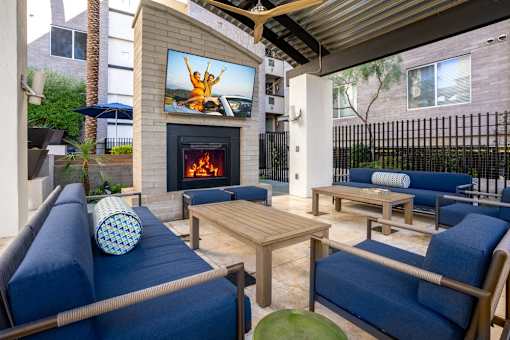 A patio with a fireplace and a television displaying a person jumping.