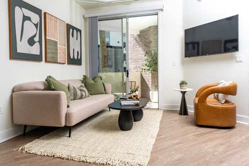 A living room with a beige couch, a coffee table, and a TV mounted on the wall.