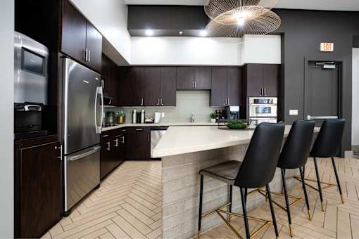 A kitchen with a white counter top and black chairs.