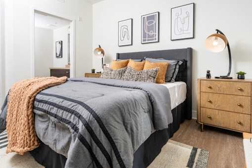 A bedroom with a large bed, a nightstand, and a lamp.