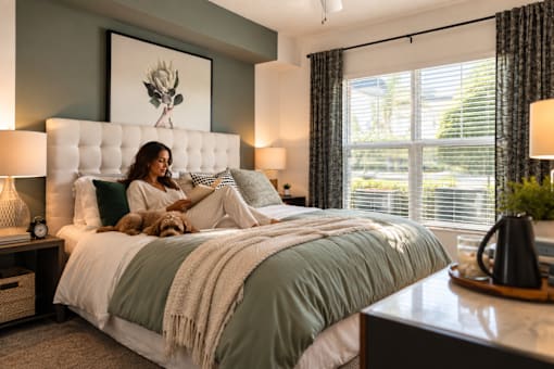A woman is sitting on a bed with a dog.