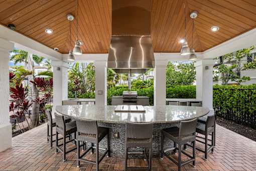 A modern outdoor dining area with a glass table surrounded by chairs.