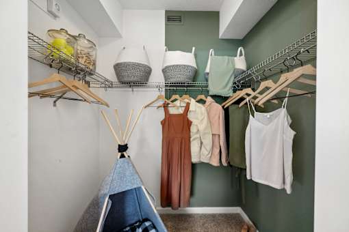 A room with a teepee and clothes hanging on a rack.