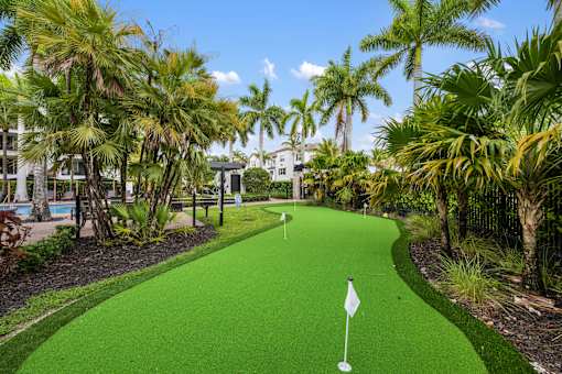 A green flag on a golf course surrounded by trees.
