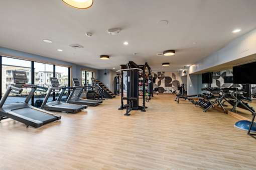 a gym with cardio equipment and a large window