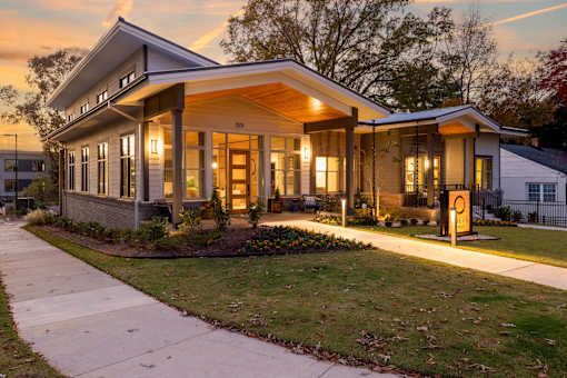 the front of a house at sunset with a sidewalk