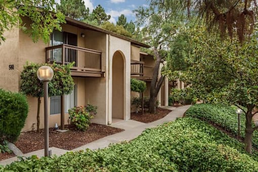 A building with a balcony and a tree in front of it.