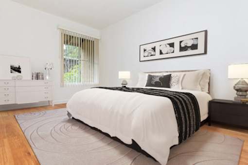 A bedroom with a large bed, a nightstand, and a dresser.