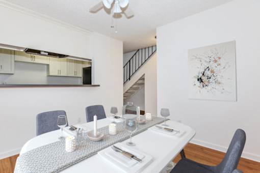 A dining room with a white table and grey chairs.