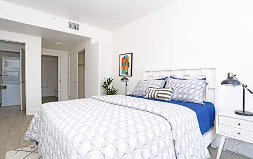 A bedroom with a white bed and a blue bedspread.