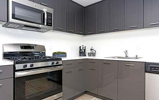 A modern kitchen with a stove, microwave, and cabinets.