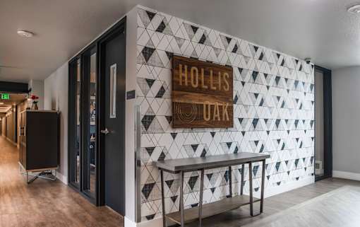 A white and black tiled wall with a sign that says "Hollis Oaks".