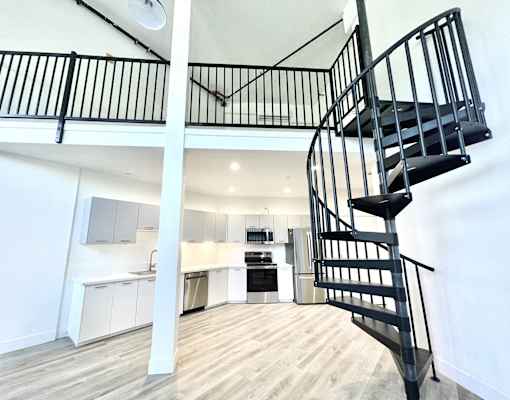 A black spiral staircase in a white room with wooden flooring.
