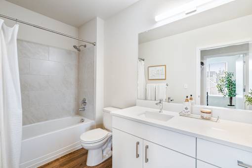a bathroom with a white sink and toilet and a white bathtub with a shower curtain and