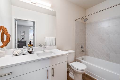 a bathroom with white cabinets and a white toilet next to a white bathtub