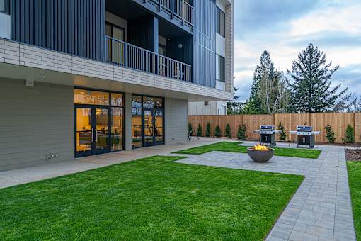 a backyard with a fire pit and a patio with two bbq pits