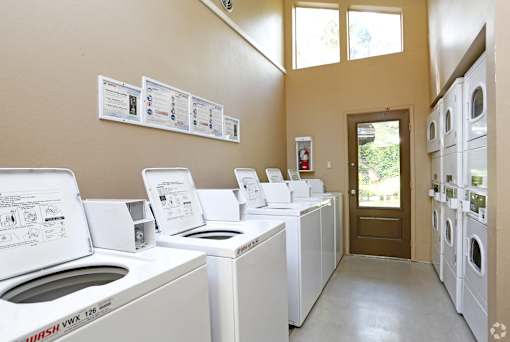 A laundromat with washers and dryers lined up.