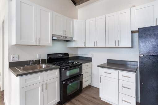 A kitchen with white cabinets and black appliances.