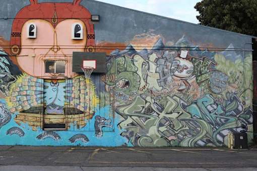 A wall with a mural of a face and a ship.