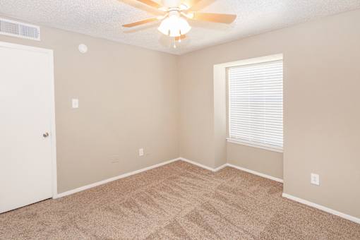 A room with a ceiling fan and carpeted floor.