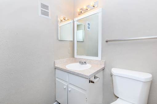 A white bathroom with a toilet, sink, and mirror.