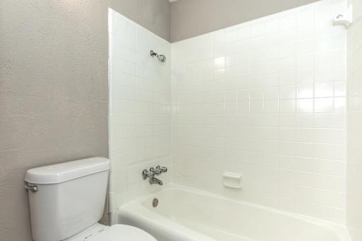 A white toilet sits next to a white bathtub in a bathroom.