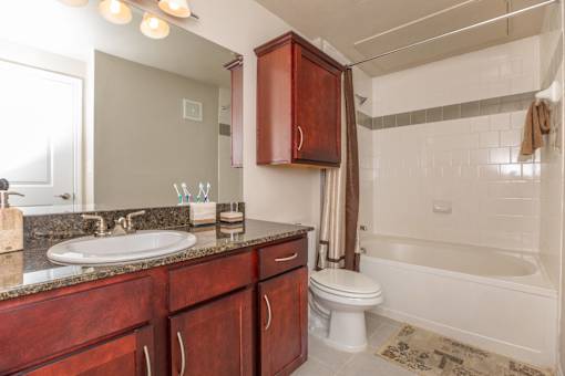 A bathroom with a white tub and a brown vanity.