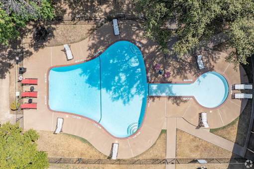 an aerial view of a swimming pool with trees and a courtyard