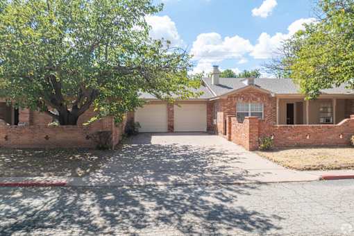 a house with a driveway and a tree in front of it