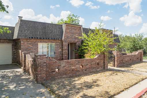 the front of a brick house with a brick wall