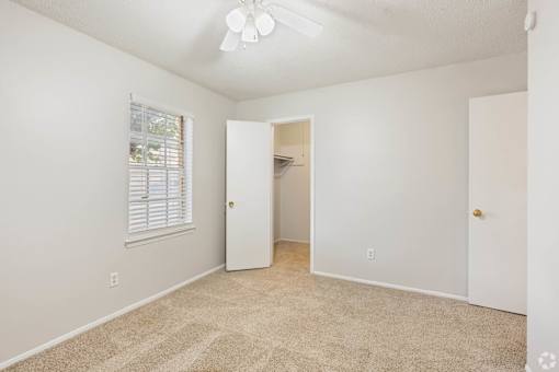 an empty bedroom with a closet and a window