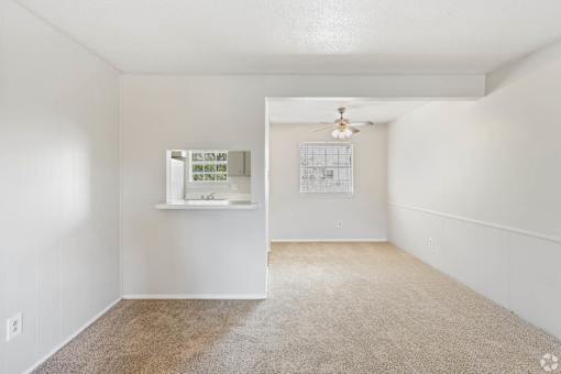 a living room with white walls and flooring and a ceiling fan