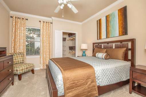 A bedroom with a bed, chair, and a painting on the wall.